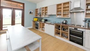 Een moderne keuken met houten kasten, een Bosch oven en een eettafel.