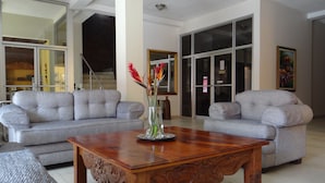 Un salón comedor amplio con dos sofás grises, una mesa de centro de madera y un jarrón con plantas decorativas.