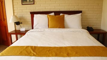 A hotel room with a bed, a nightstand with a lamp, and a picture on the wall.