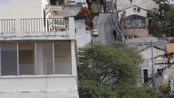 Un immeuble d’habitation avec un toit en pente, un escalier apparent et une voiture garée.