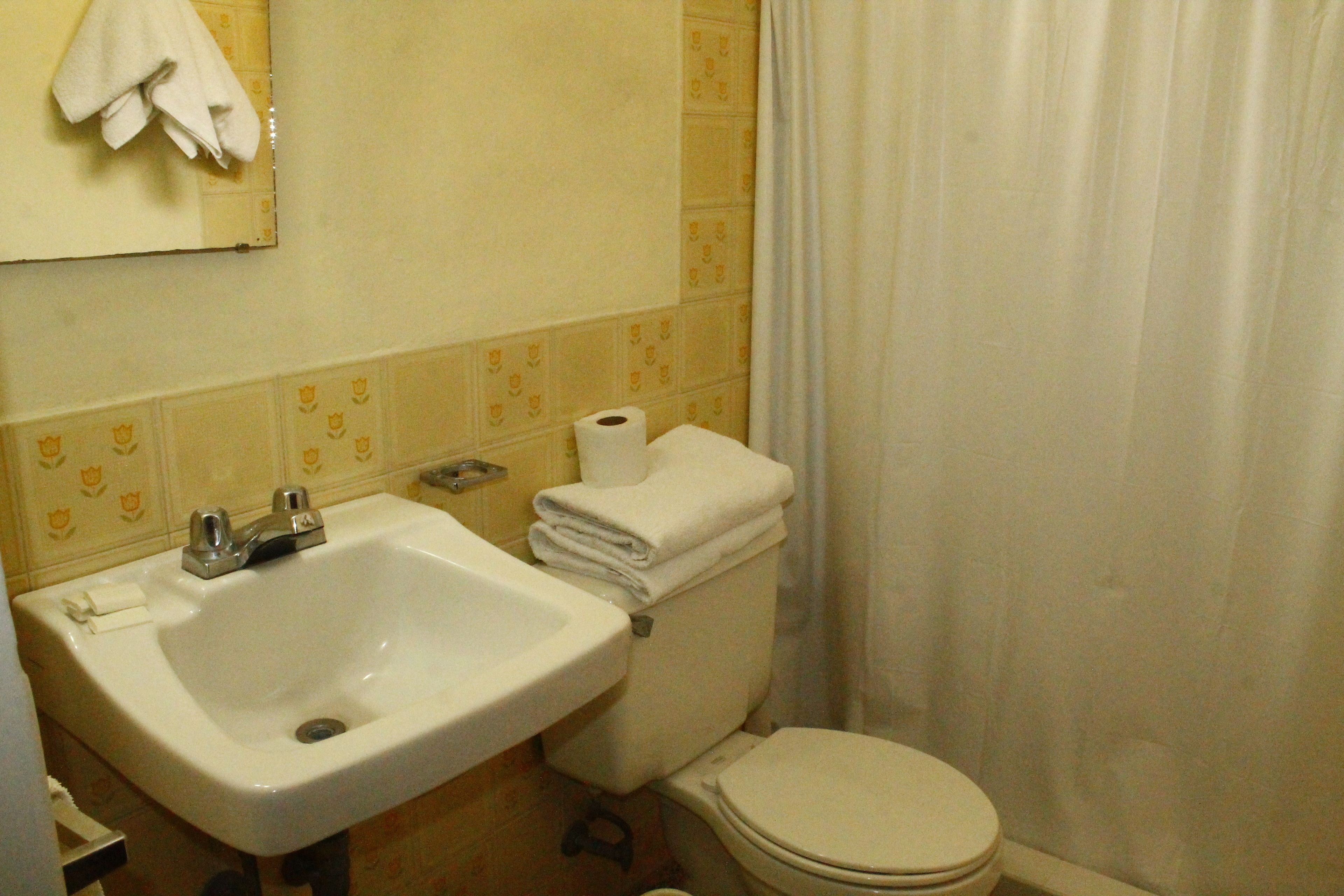 Un baño con lavamanos, inodoro y una toalla colgada en la pared.