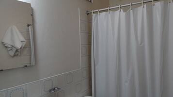 A bathroom with a toilet, a sink, a mirror, and a shower curtain.