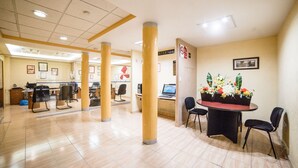 A spacious lobby with a reception desk, several computer workstations, and a decorative plant arrangement. - Hotel Elizabeth Central (Aguascalientes)