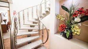 A spiral staircase with metal railings and a potted plant with flowers on the landing. - Hotel Elizabeth Central (Aguascalientes)