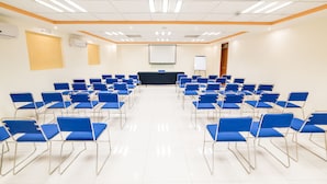 A conference room with rows of blue chairs, a projector screen, and a whiteboard. - Hotel Elizabeth Central (Aguascalientes)