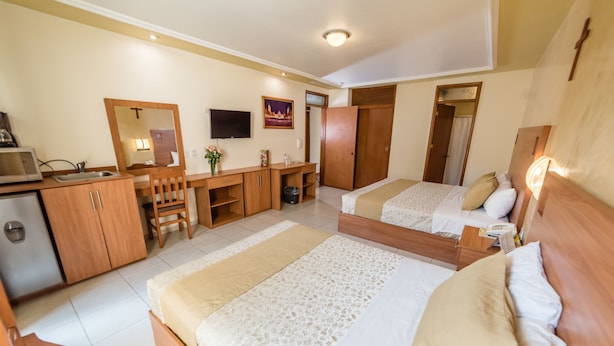 A hotel room with two beds, a desk with a chair, a television, and a small kitchenette. - Hotel Elizabeth Central (Aguascalientes)