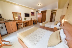 A hotel room with two beds, a desk with a chair, a television, and a small kitchenette. - Hotel Elizabeth Central (Aguascalientes)