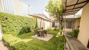 A patio area with a table and chairs under a canopy, surrounded by well-maintained hedges and a small tree. - Hotel Elizabeth Central (Aguascalientes)