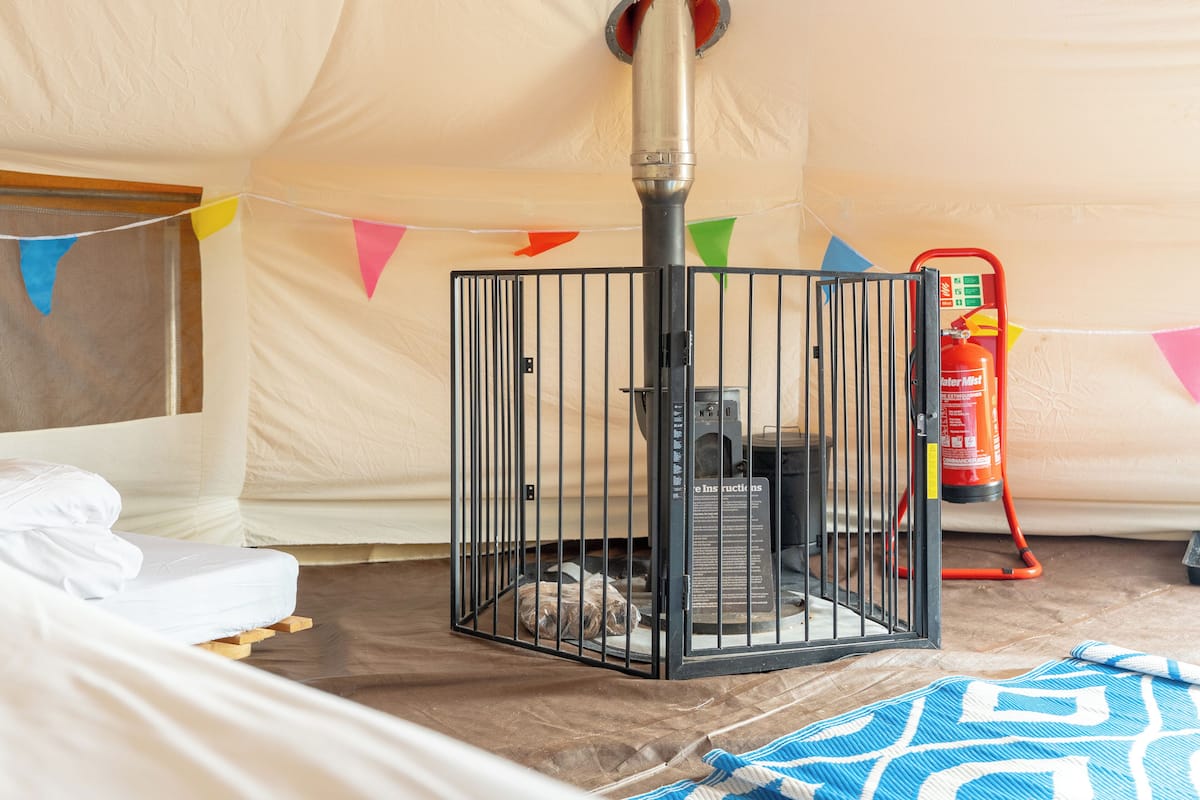 A tent with a metal cage, a fire extinguisher, and a bed with a white mattress.
