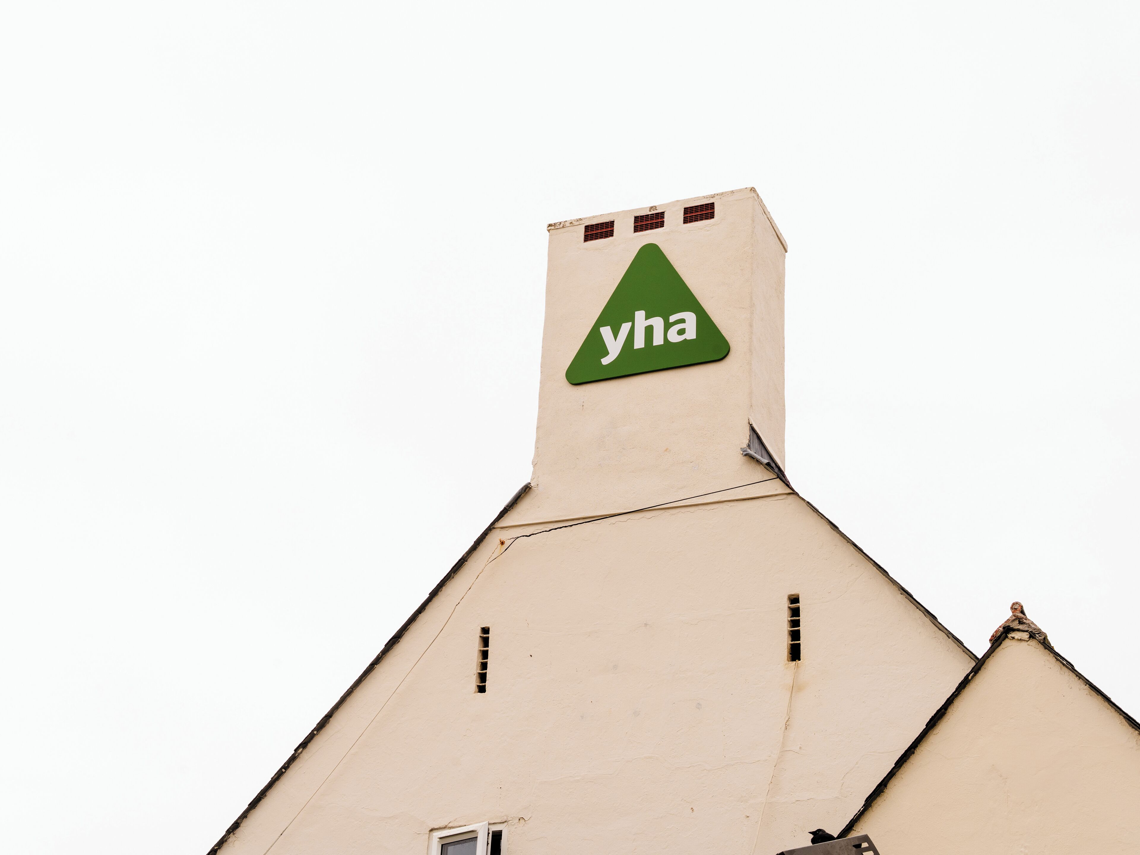 A building with a triangular roof and a green triangular sign with the text 'yha'.