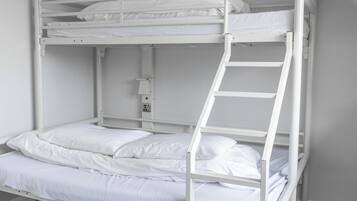 A bunk bed with a ladder, white bedding, and a small shelf with a light fixture.
