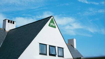 Ein Haus mit einem dreieckigen Dach, einem Schornstein und einem Fenster mit dem Schriftzug 'yha'.
