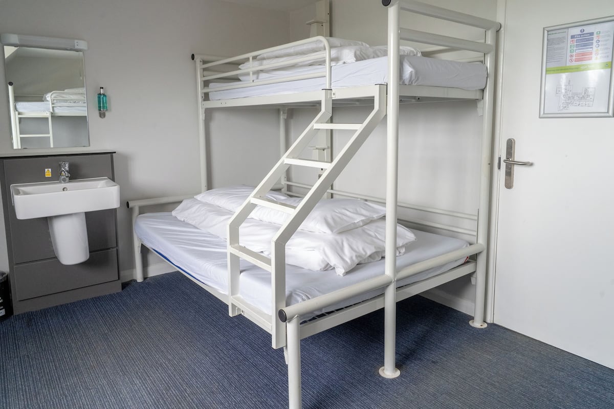 A bunk bed room with a sink and a mirror.