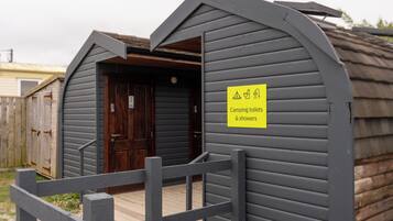 A small wooden structure with a sign indicating camping toilets and showers.
