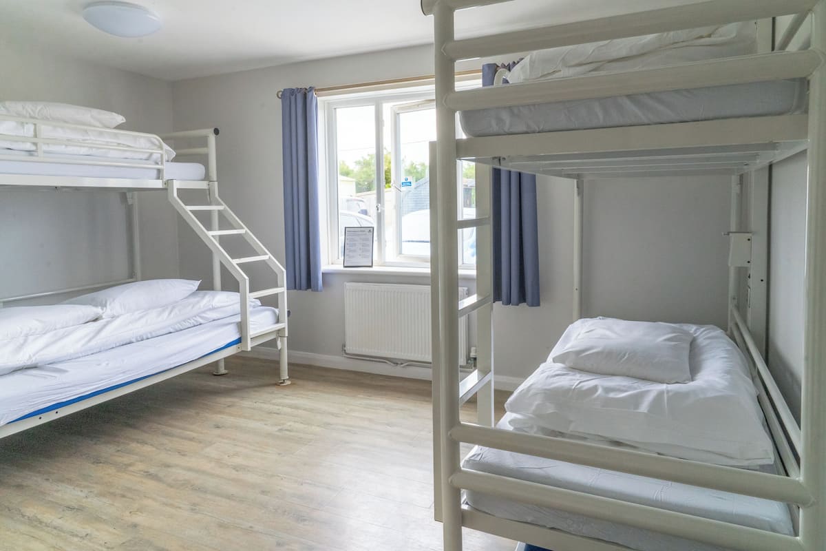 A bunk bed room with a window, a radiator, and a staircase.