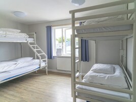 A bunk bed room with a window, a radiator, and a staircase.
