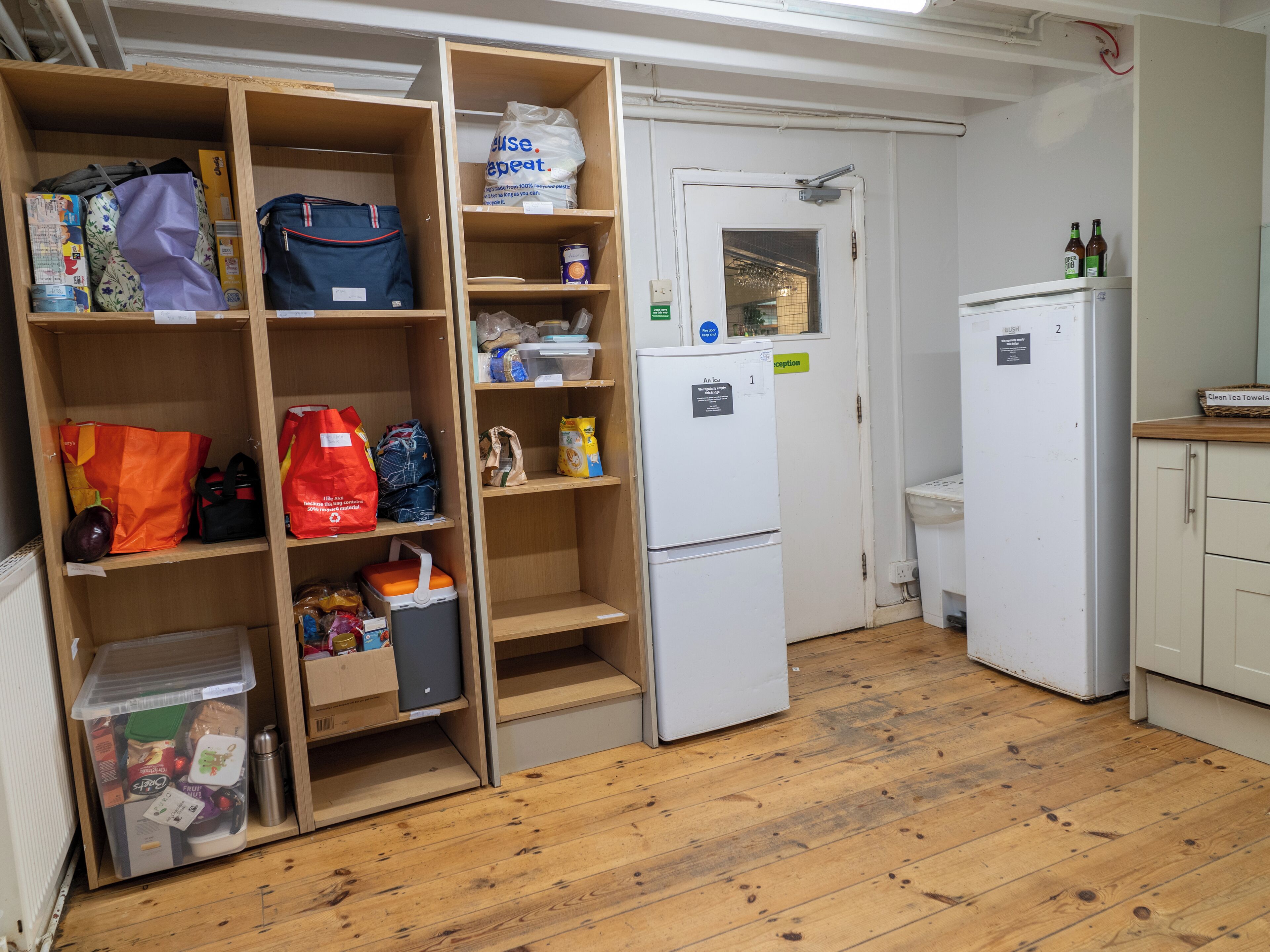 Una cocina compacta con armarios de madera, un refrigerador y un lavamanos.