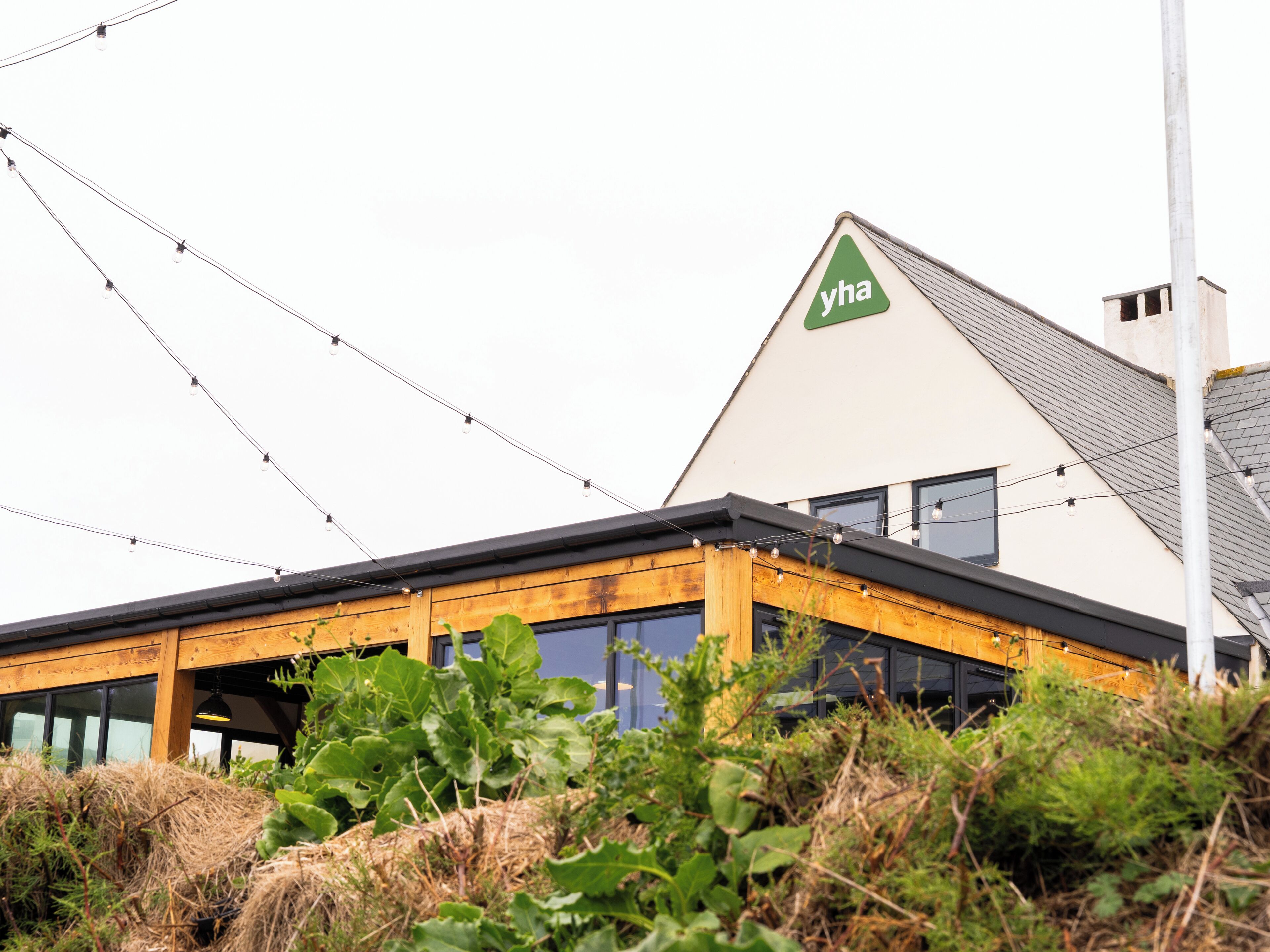 A modern building with a triangular roof, a visible logo, and a string of lights.