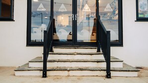 Entrada de un edificio con puertas de vidrio, una escalera y un letrero que dice '6dly'.