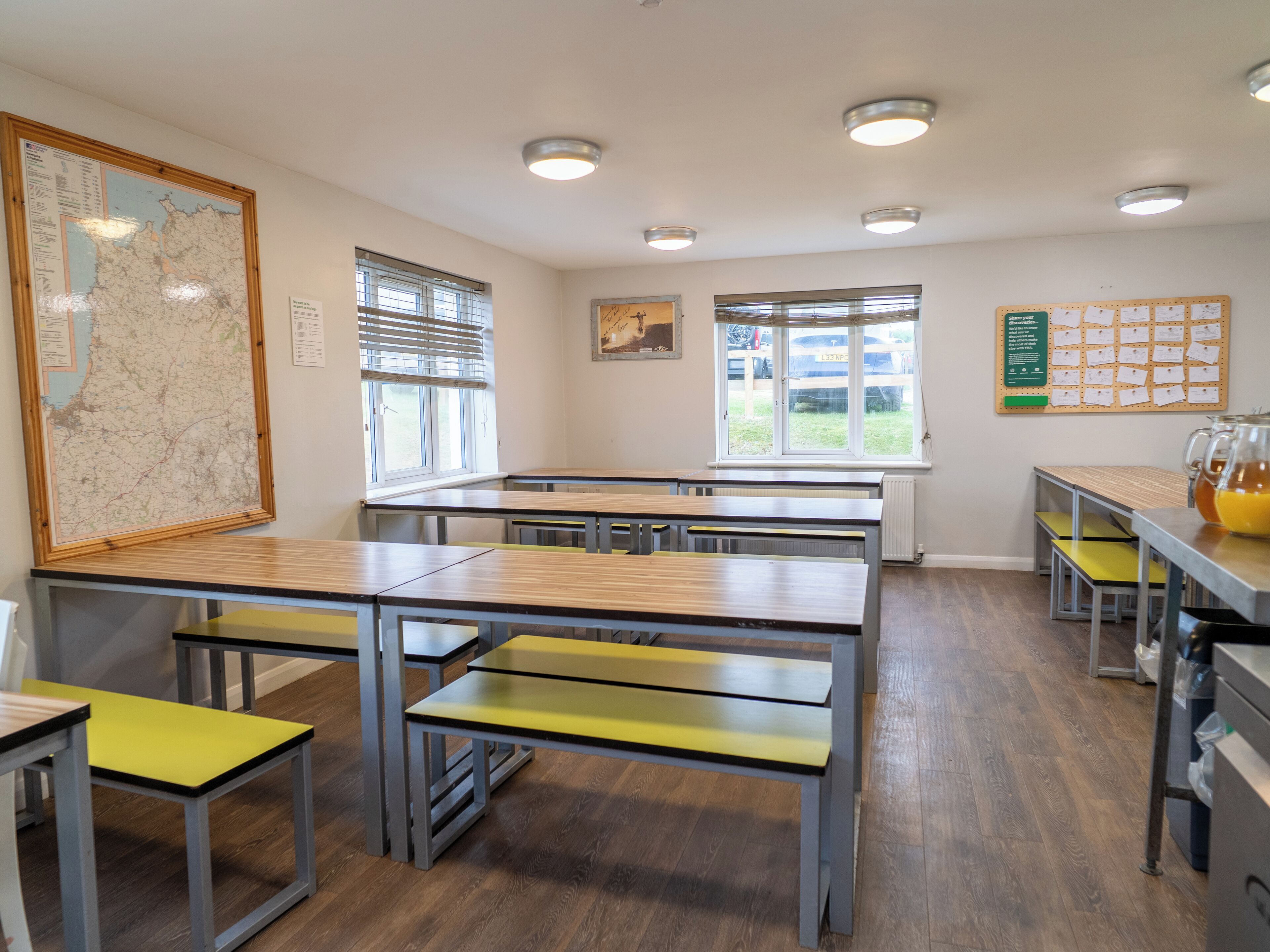 Une salle de classe avec des bureaux, une carte accrochée au mur et un tableau d’affichage où sont épinglées des notes.