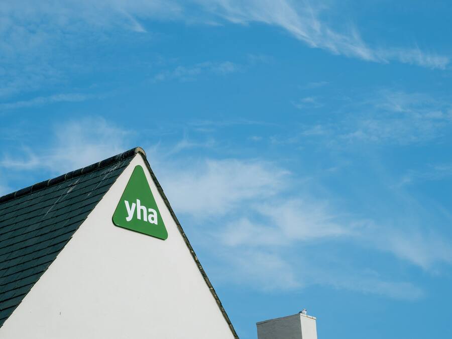 A building with a green triangular sign with the letters "yha" on a white background.