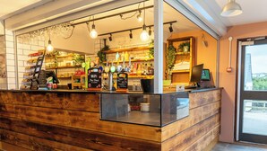 Una barra de madera con un frente de vidrio, estantes con botellas y vasos, y un cartel que indica acceso a WiFi.