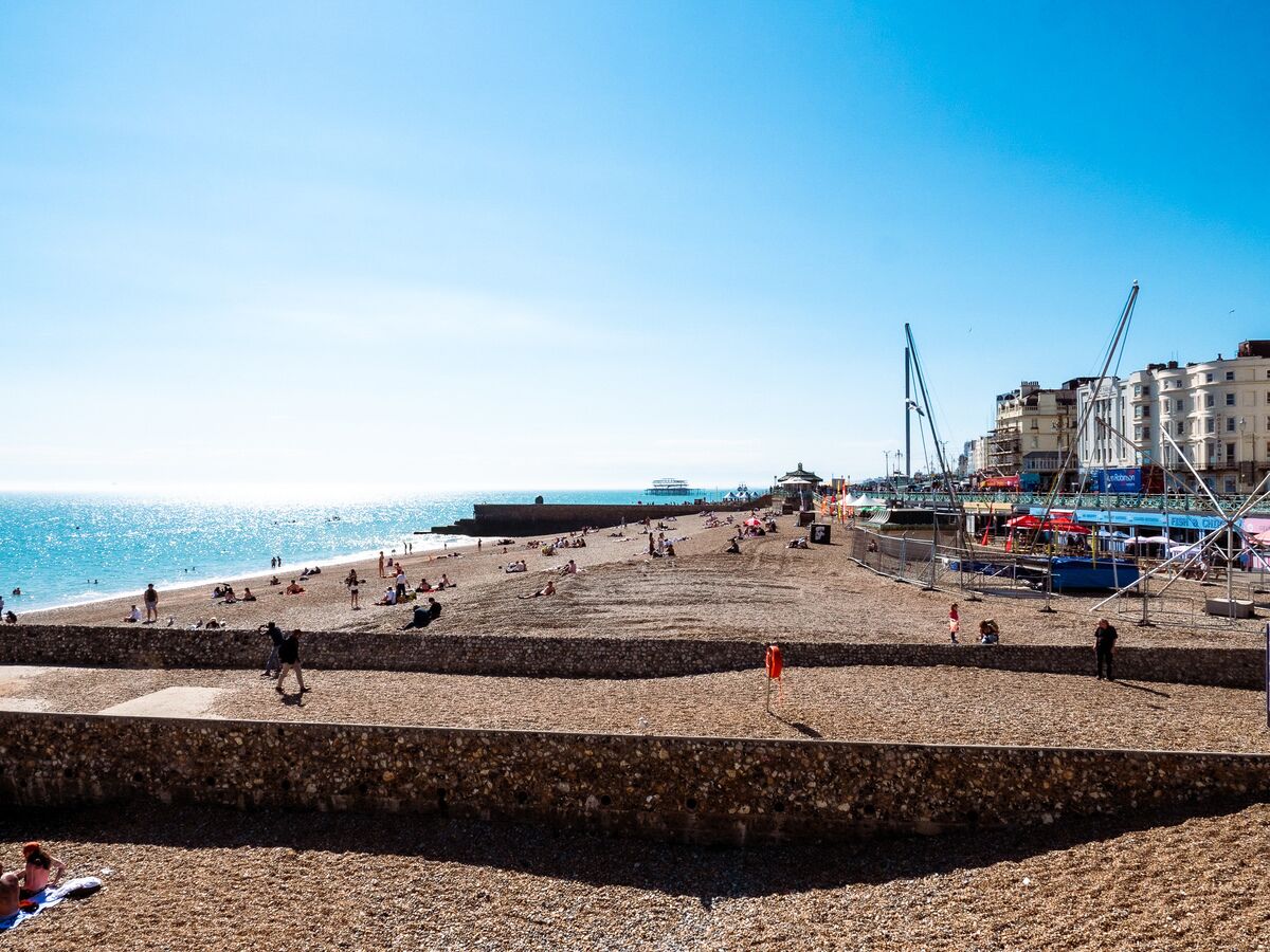 A beach with people relaxing and walking along the shore.