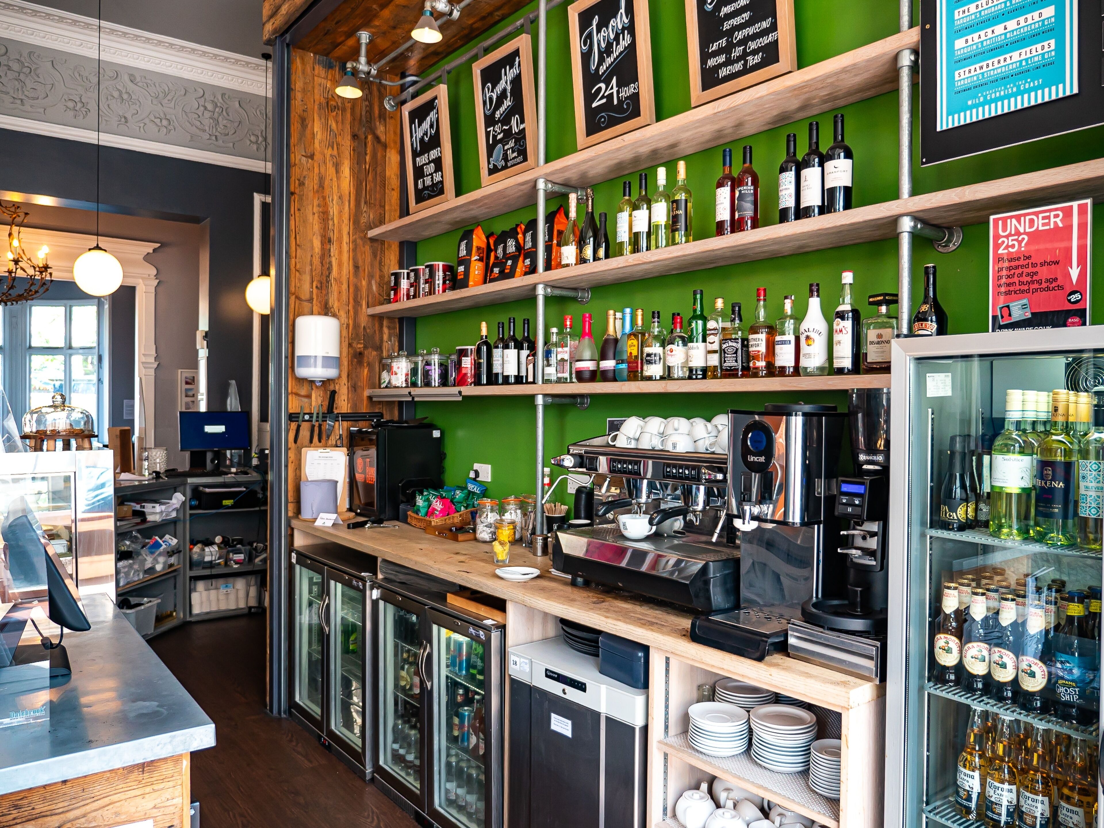 A bar area with shelves of liquor bottles, a coffee machine, and a refrigerated display.