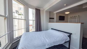 A bedroom with a bed, a window, a wall-mounted TV, and a power outlet.