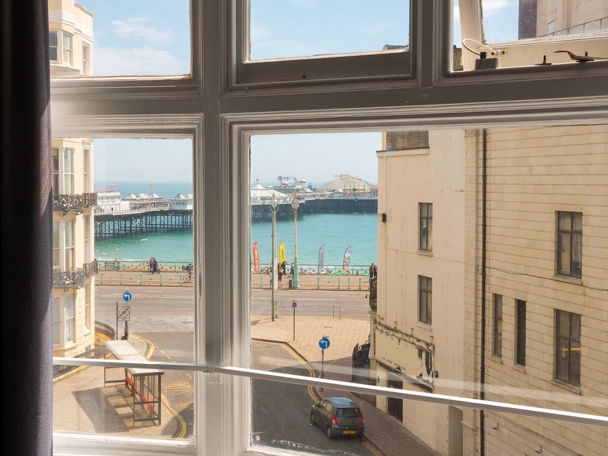 A view from a window overlooking a coastal area with a pier, buildings, and a road.