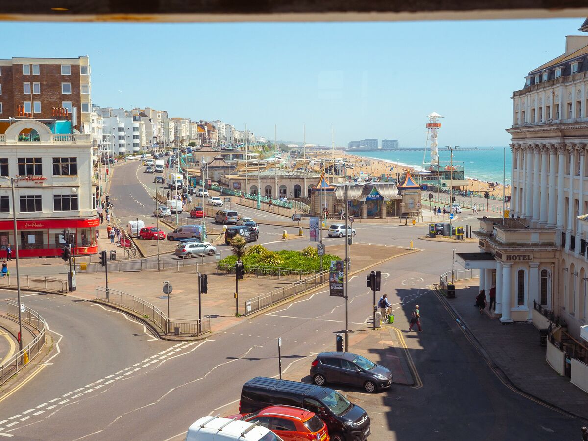 Un paisaje urbano costero con un hotel destacado, una intersección concurrida y una playa al fondo.