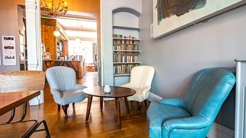 Un rincón acogedor para leer, con sillones de cuero, una mesa de madera y una estantería llena de libros.