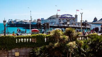 A waterfront promenade with a prominent building labeled "Brighton Palace Pier," featuring a classic architectural style with a dome and flags.