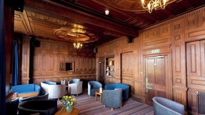 A hotel lobby with wooden paneling, a chandelier, and modern seating. - YHA Swanage - Hostel (Swanage)
