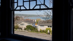 A window with a view of a residential area, houses, and a body of water. - YHA Swanage - Hostel (Swanage)