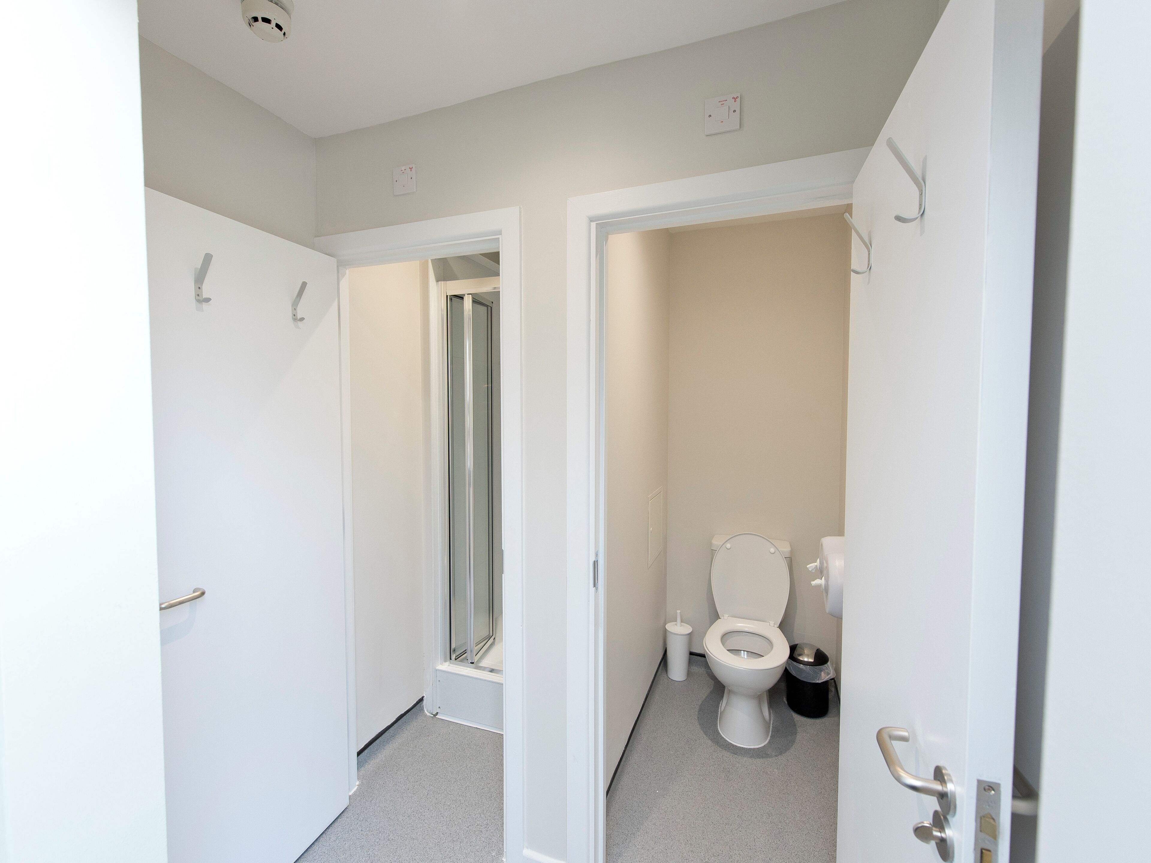 A bathroom with a toilet, a trash bin, and a shower area.