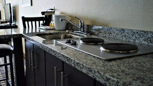 Una cocina con encimeras de granito, un lavamanos de acero inoxidable y una cafetera.