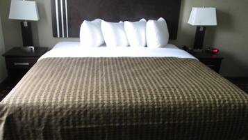 Ein Hotelzimmer mit einem großen Bett, zwei Nachttischen mit Lampen und einem dunklen Kopfteil.