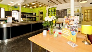 Un restaurante con decoración verde, una barra con menú y un cartel que ofrece un descuento del 20%.