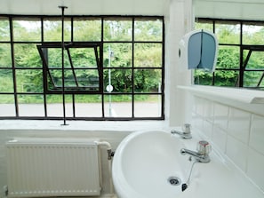 A bathroom with a large window, a white sink, and a radiator.