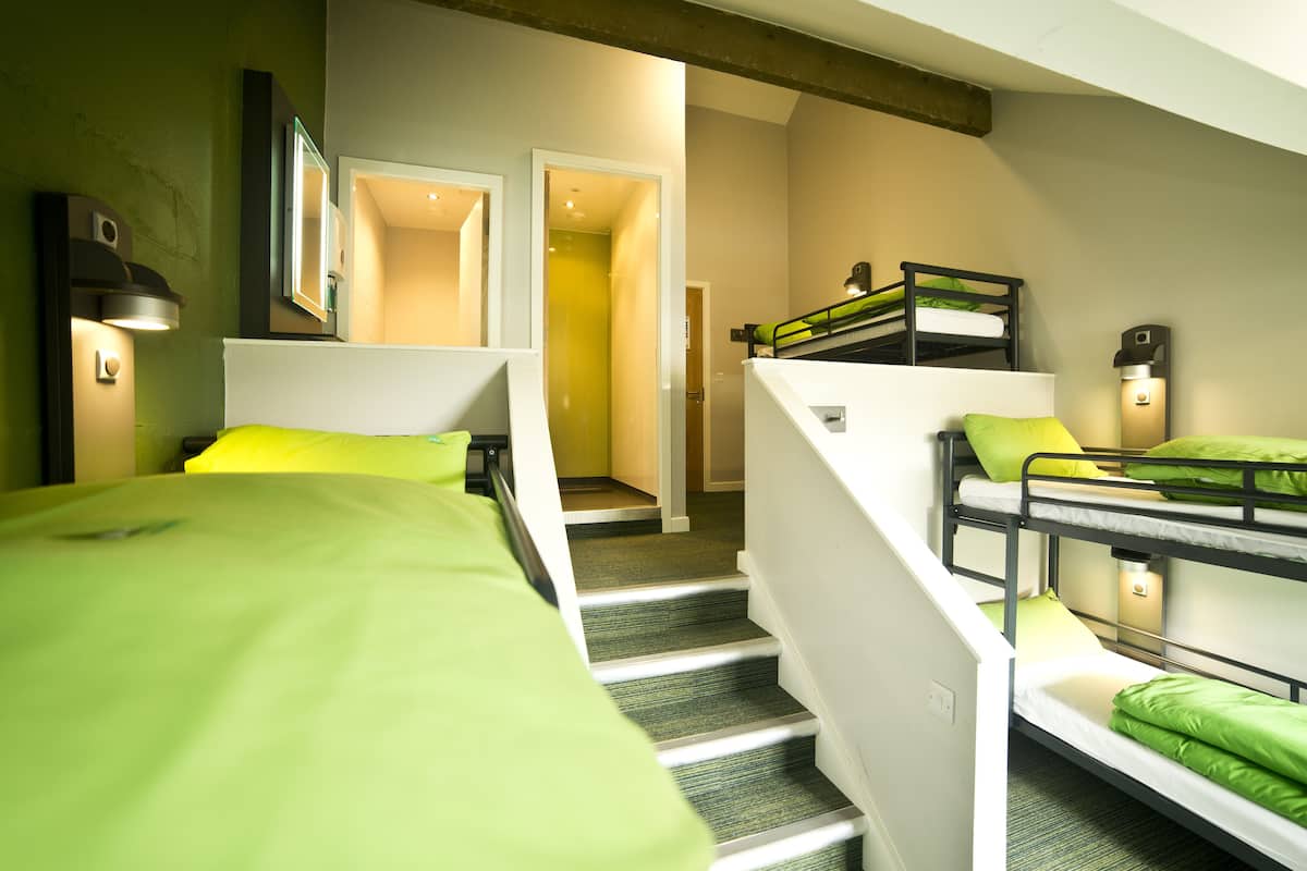 A hotel room with bunk beds, a staircase, and a hallway leading to another room.