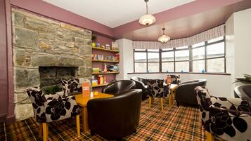 A cozy room with a stone fireplace, a bookshelf, plaid carpet, and comfortable seating.