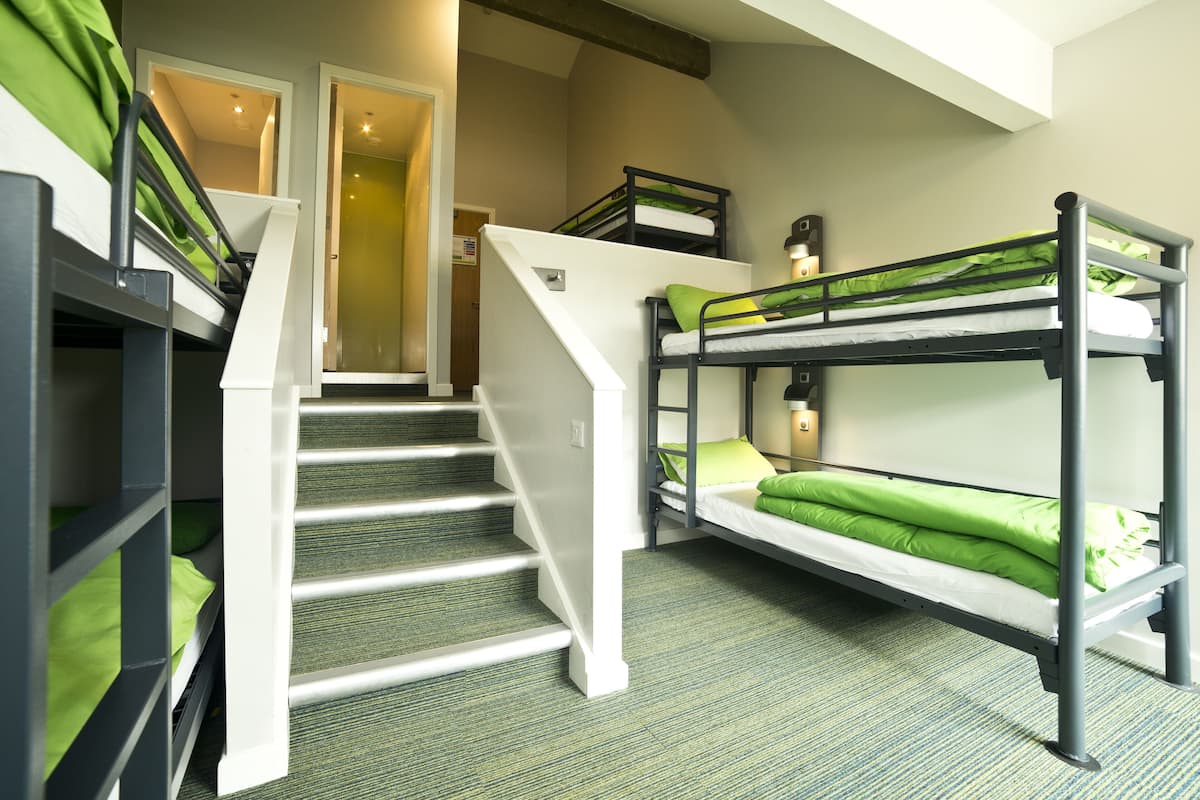 A room with bunk beds, a staircase, and a carpeted floor.