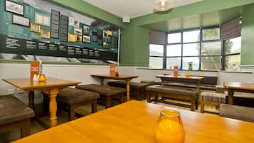 Un comedor acogedor con mesas y bancos de madera, una pared grande con información y vistas amplias a través de grandes ventanales.