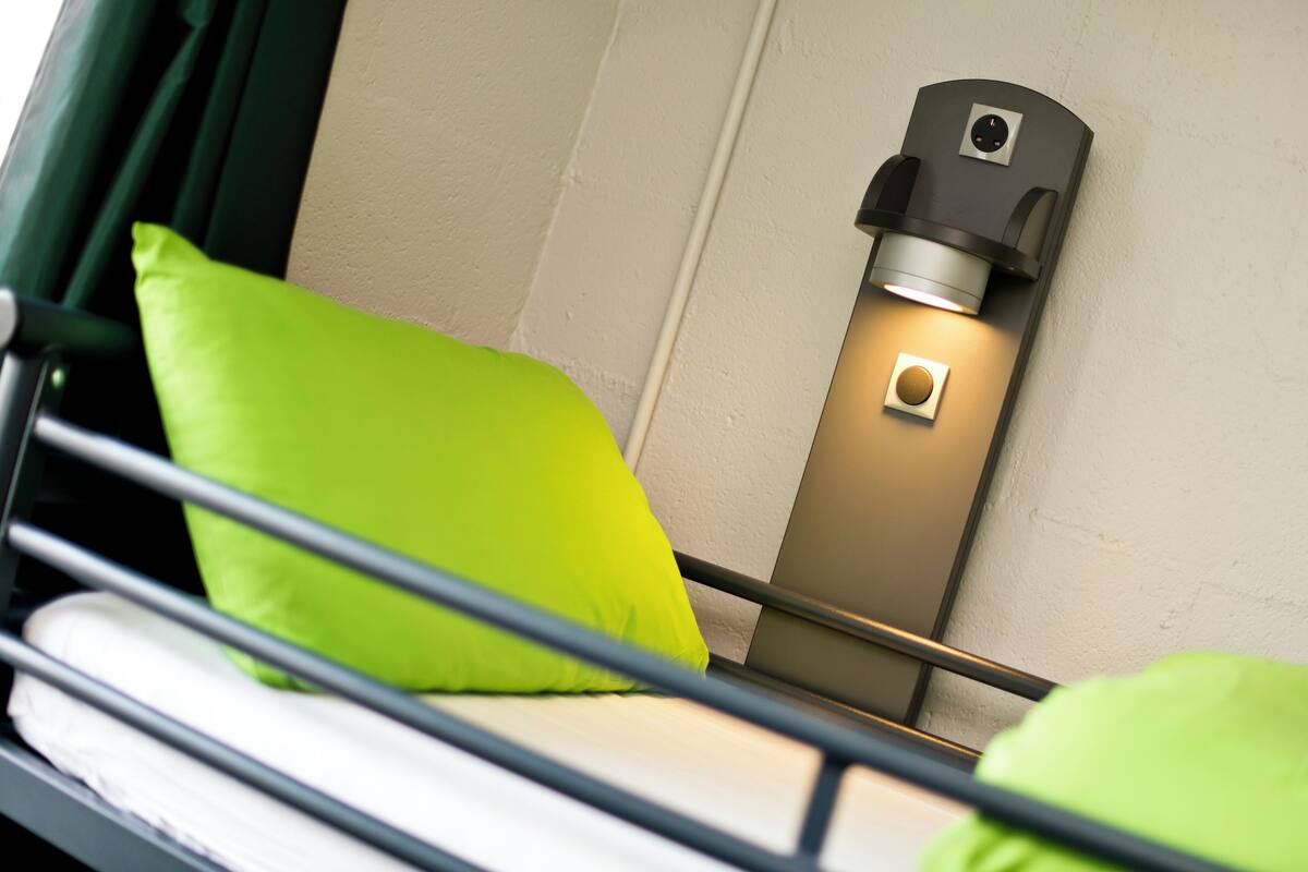 A bed with green pillows and a wall-mounted light fixture.