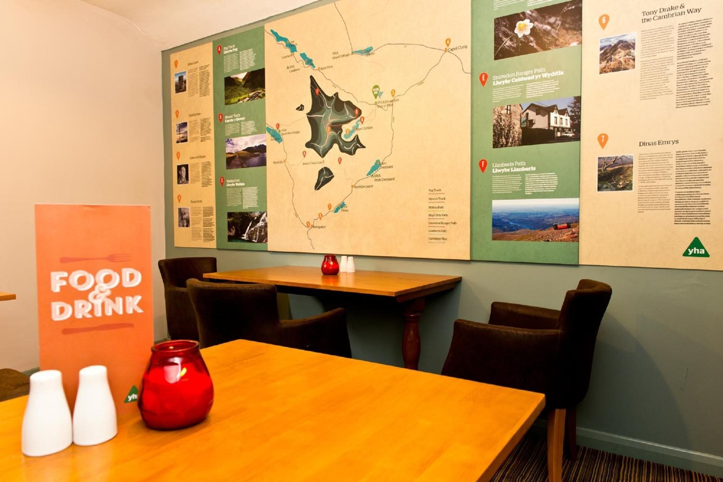 Un ristorante con una mappa e un pannello informativo a parete, un tavolo di legno e un vaso rosso.