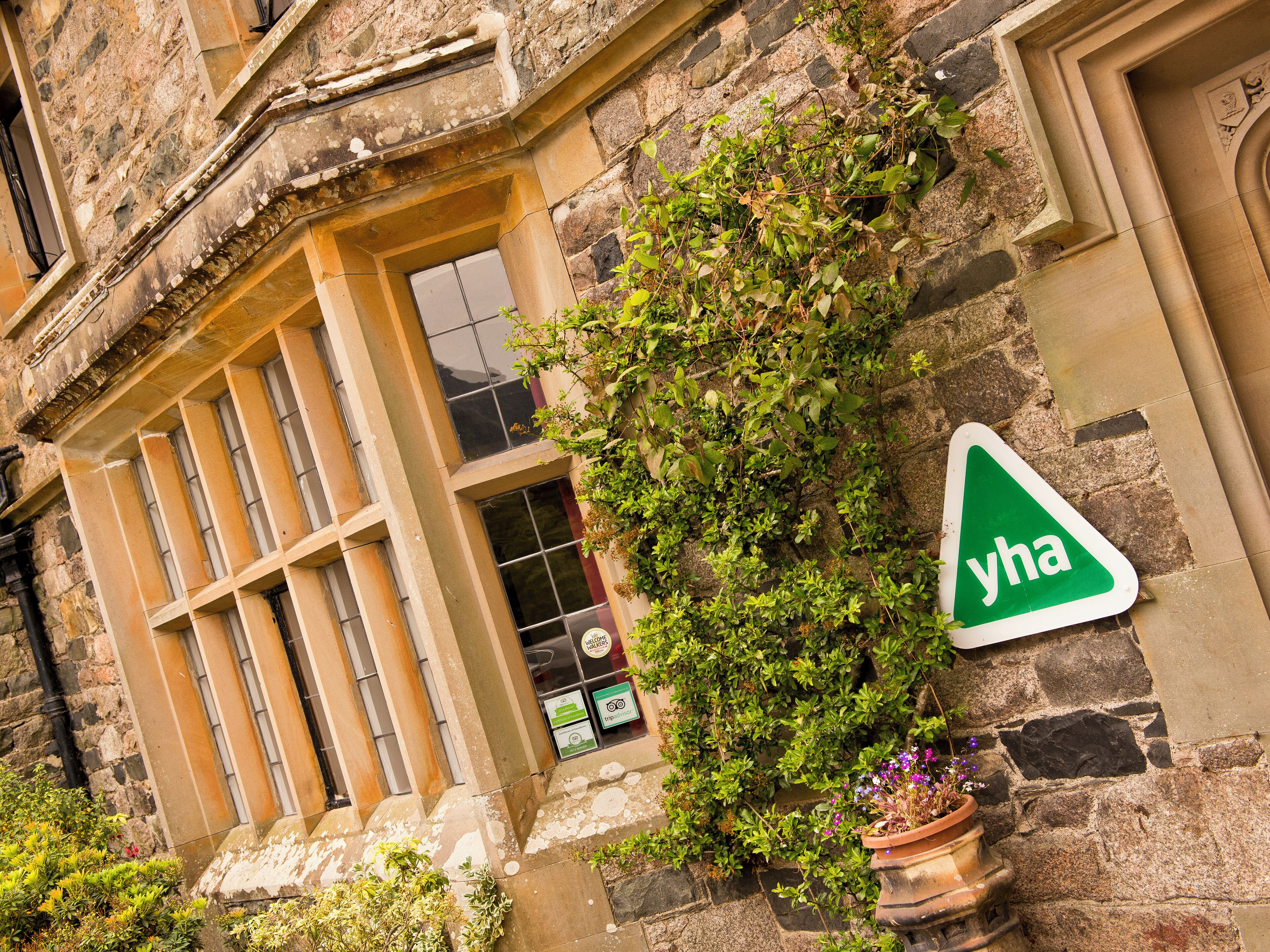 A stone building with a window and a green sign reading "yha".