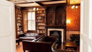 Une bibliothèque dotée de canapés en cuir, d’étagères, d’une cheminée et de boiseries décoratives.