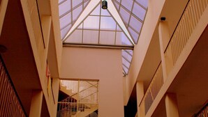 Un atrio de varios niveles con techo de cristal, escaleras y barandillas.