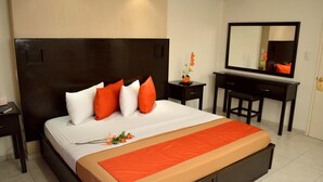 Una habitación de hotel con una cama grande, un escritorio y un espejo.